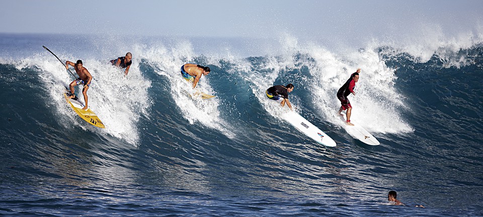Surfers riding a wave at Teahupo’o, Paea, Tahiti