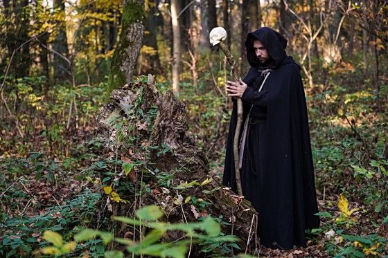 Man wearing black cloak wielding a skull staff
